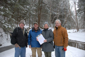 Bison Hollow SNP Dedication, group of four smiling in the snow with paperwork
